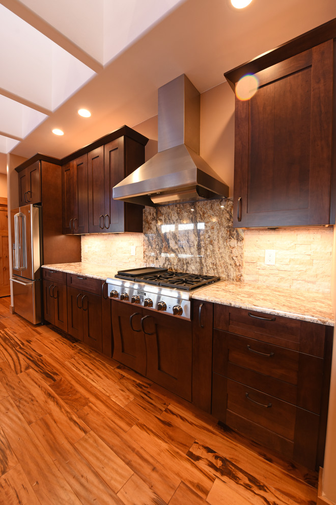 Example of a mid-sized transitional galley medium tone wood floor open concept kitchen design in Other with an undermount sink, shaker cabinets, dark wood cabinets, granite countertops, beige backsplash, stone tile backsplash, stainless steel appliances and an island