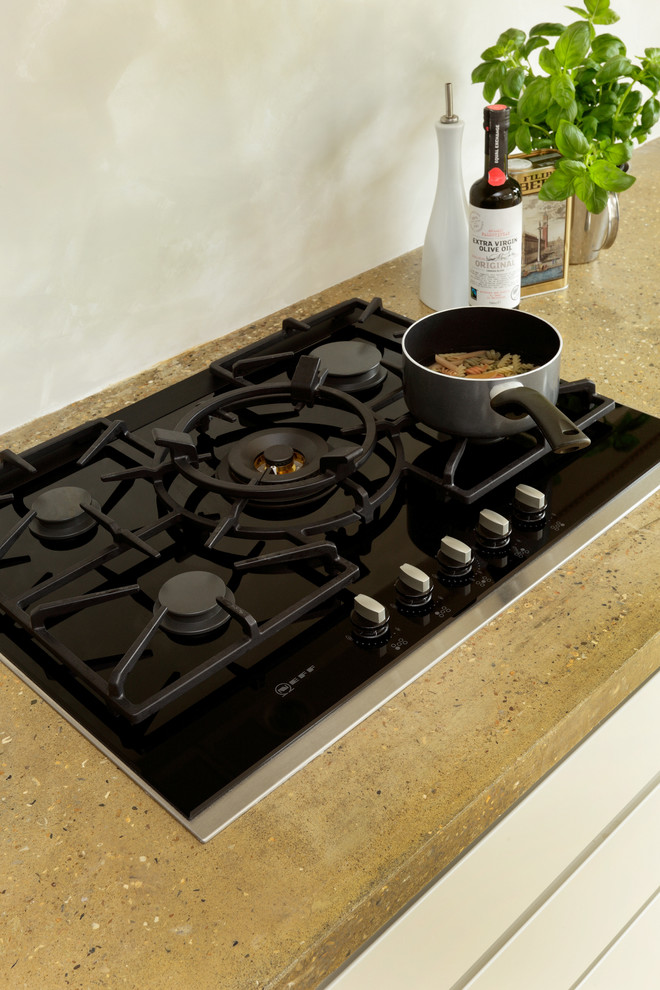 Immagine di una cucina contemporanea con ante lisce, ante bianche, top in cemento e elettrodomestici da incasso