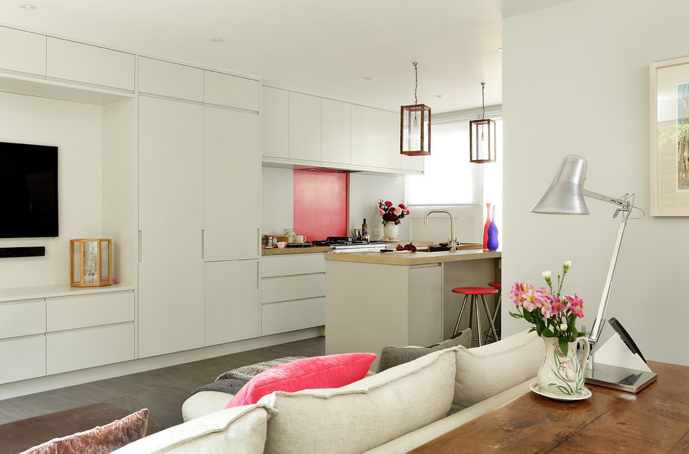 На фото: прямая кухня-гостиная в современном стиле с плоскими фасадами, серыми фасадами, столешницей из бетона, розовым фартуком, техникой под мебельный фасад, полом из керамогранита и островом с