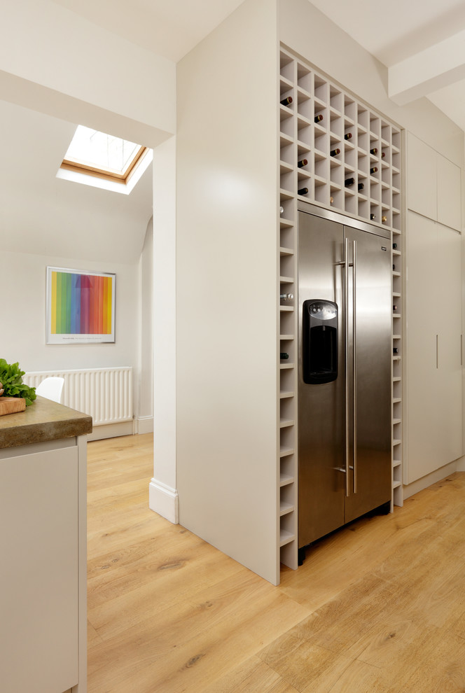 Moderne Wohnküche mit flächenbündigen Schrankfronten, weißen Schränken, Betonarbeitsplatte, Elektrogeräten mit Frontblende und Kücheninsel in London