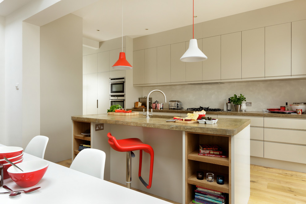 This is an example of a contemporary kitchen/diner in London with flat-panel cabinets, white cabinets, concrete worktops, integrated appliances and an island.