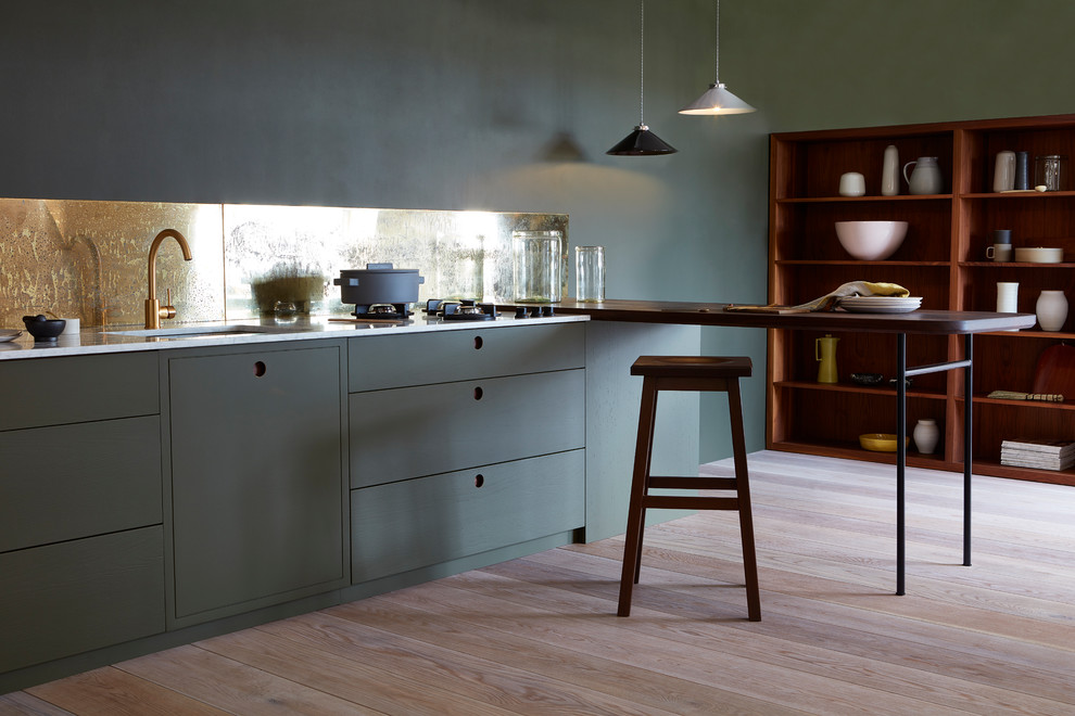 Inspiration for a medium sized contemporary single-wall open plan kitchen in Other with a submerged sink, flat-panel cabinets, green cabinets, marble worktops, metallic splashback, light hardwood flooring and no island.