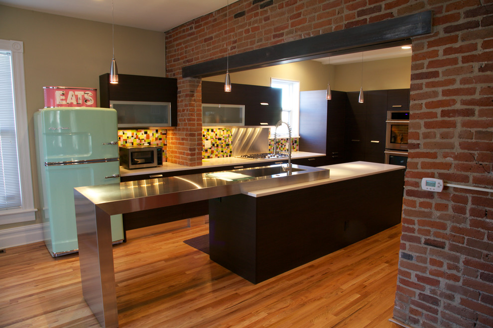 Exempel på ett stort industriellt kök, med en integrerad diskho, släta luckor, skåp i mörkt trä, bänkskiva i kvarts, flerfärgad stänkskydd, stänkskydd i glaskakel, färgglada vitvaror, mellanmörkt trägolv och en köksö