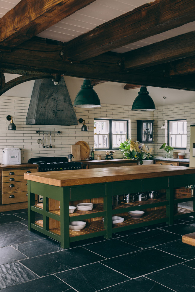 ロンドンにあるカントリー風のおしゃれなキッチン (エプロンフロントシンク、オープンシェルフ、緑のキャビネット、木材カウンター、白いキッチンパネル、サブウェイタイルのキッチンパネル、グレーの床) の写真