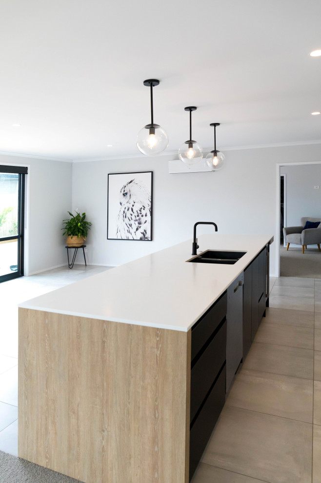 This is an example of a medium sized scandinavian galley kitchen/diner in Auckland with a double-bowl sink, flat-panel cabinets, black cabinets, composite countertops, black splashback, mosaic tiled splashback, stainless steel appliances, porcelain flooring, an island, grey floors and white worktops.