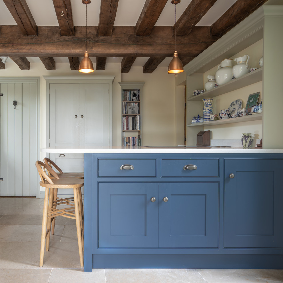 Ejemplo de cocina campestre con armarios estilo shaker, puertas de armario azules, suelo beige y encimeras blancas