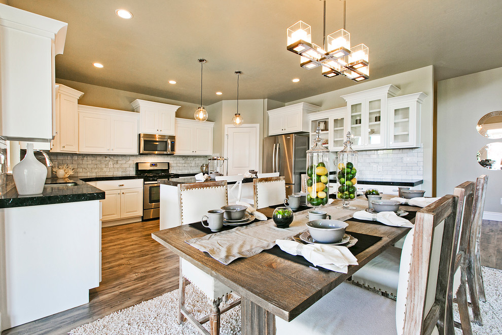 Mid-sized arts and crafts l-shaped medium tone wood floor and brown floor eat-in kitchen photo in Salt Lake City with a double-bowl sink, recessed-panel cabinets, white cabinets, quartz countertops, white backsplash, porcelain backsplash, stainless steel appliances, an island and black countertops