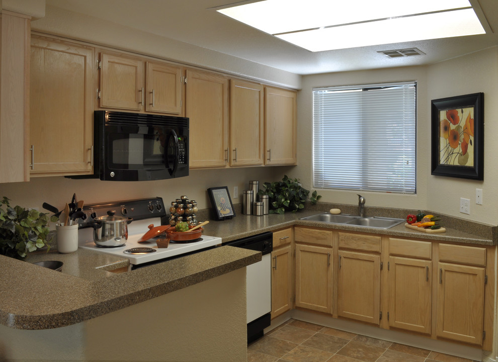 Example of a mid-sized tuscan l-shaped laminate floor enclosed kitchen design in Phoenix with a double-bowl sink, recessed-panel cabinets, light wood cabinets, laminate countertops and a peninsula