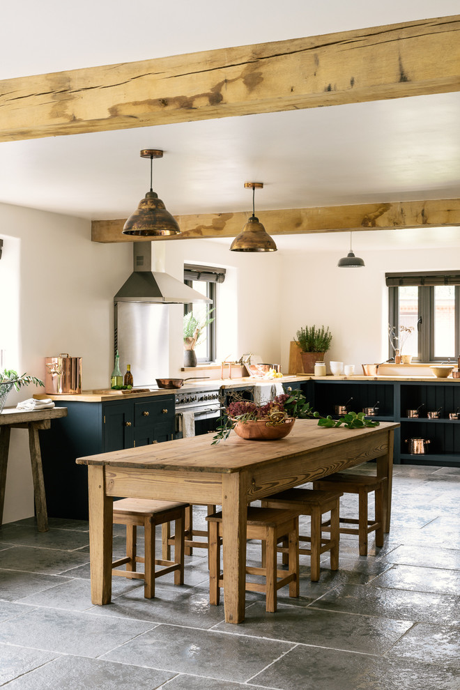 Medium sized rural l-shaped kitchen/diner in Other with a belfast sink, shaker cabinets, blue cabinets, wood worktops, stainless steel appliances, limestone flooring and no island.