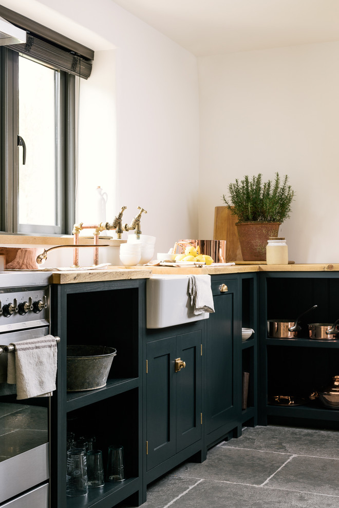Idéer för ett mellanstort lantligt kök, med en rustik diskho, skåp i shakerstil, blå skåp, träbänkskiva, rostfria vitvaror och kalkstensgolv