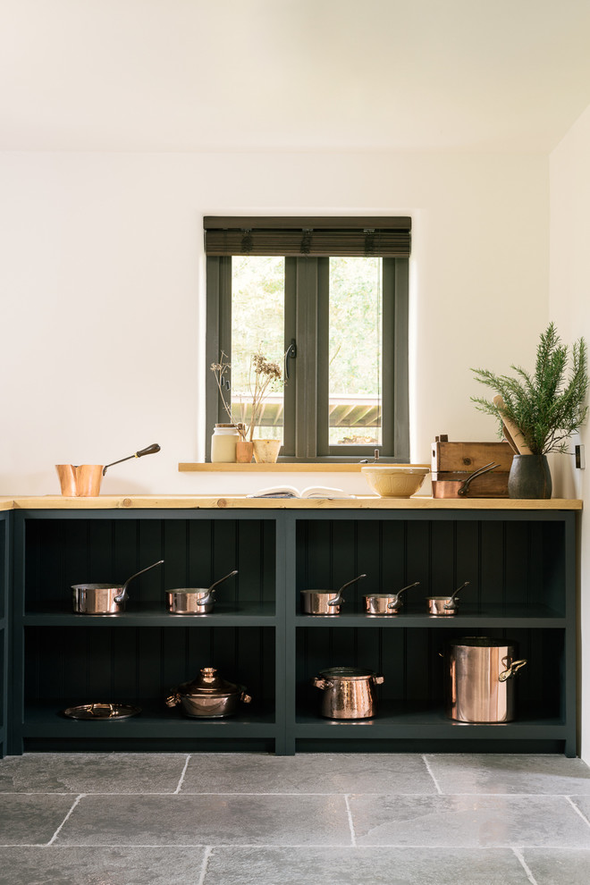 Bild på ett mellanstort lantligt kök, med en rustik diskho, skåp i shakerstil, blå skåp, träbänkskiva, rostfria vitvaror och kalkstensgolv