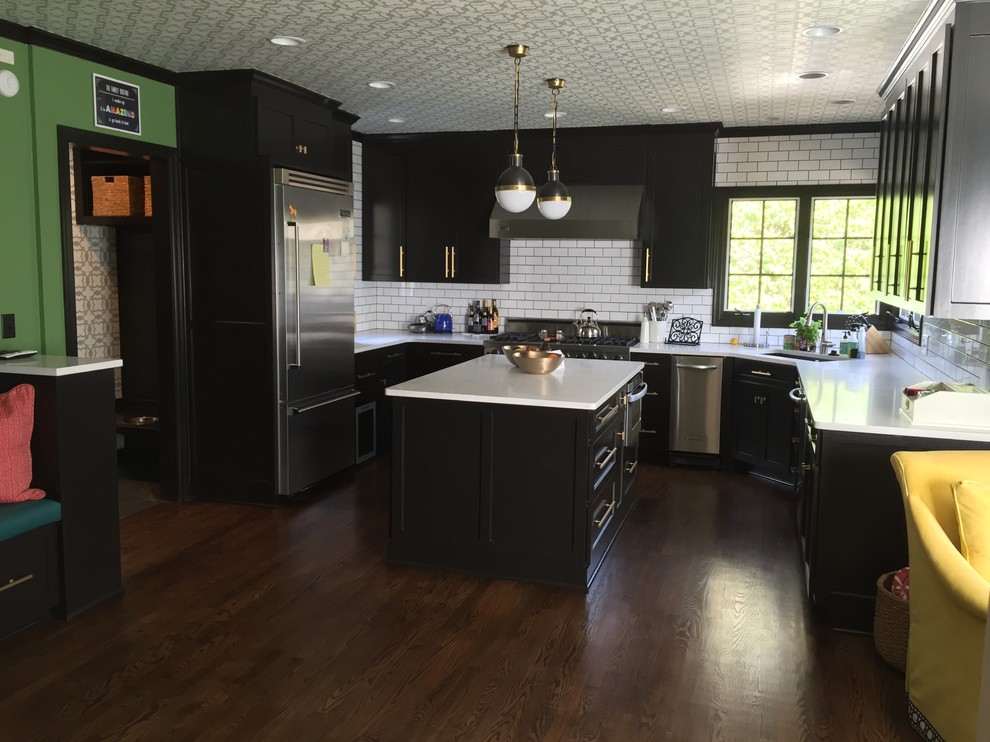 カンザスシティにある高級な広いエクレクティックスタイルのおしゃれなキッチン (アンダーカウンターシンク、黒いキャビネット、クオーツストーンカウンター、白いキッチンパネル、サブウェイタイルのキッチンパネル、シルバーの調理設備、無垢フローリング、茶色い床、白いキッチンカウンター、壁紙) の写真