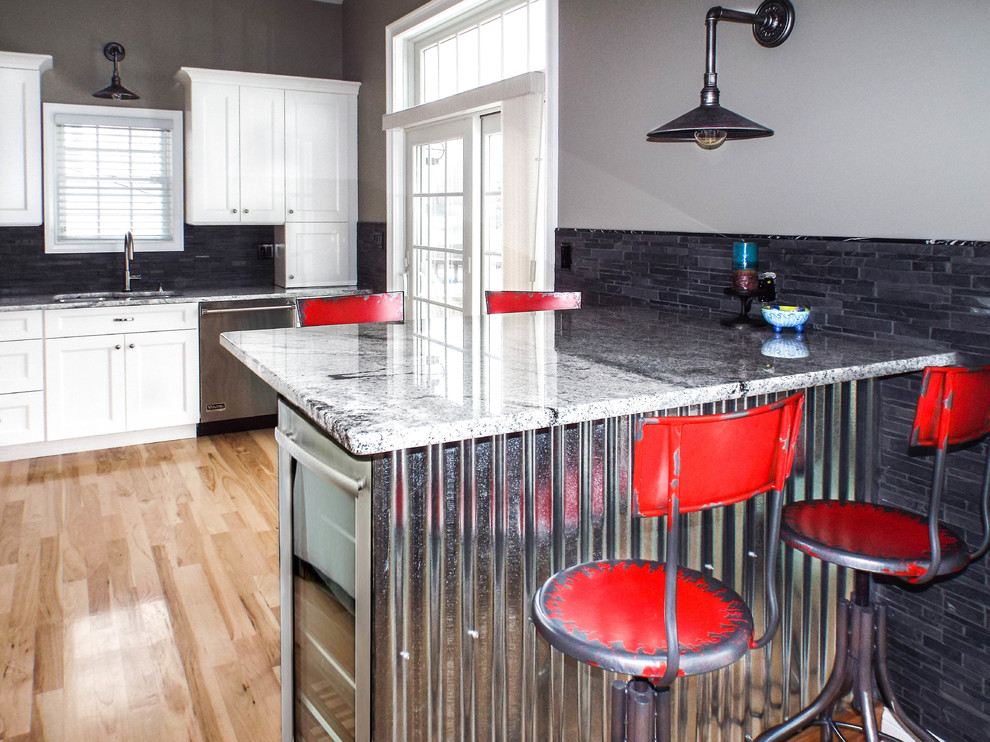 Eat-in kitchen - large industrial l-shaped light wood floor eat-in kitchen idea in New York with a drop-in sink, recessed-panel cabinets, white cabinets, granite countertops, gray backsplash, stone tile backsplash, stainless steel appliances and a peninsula