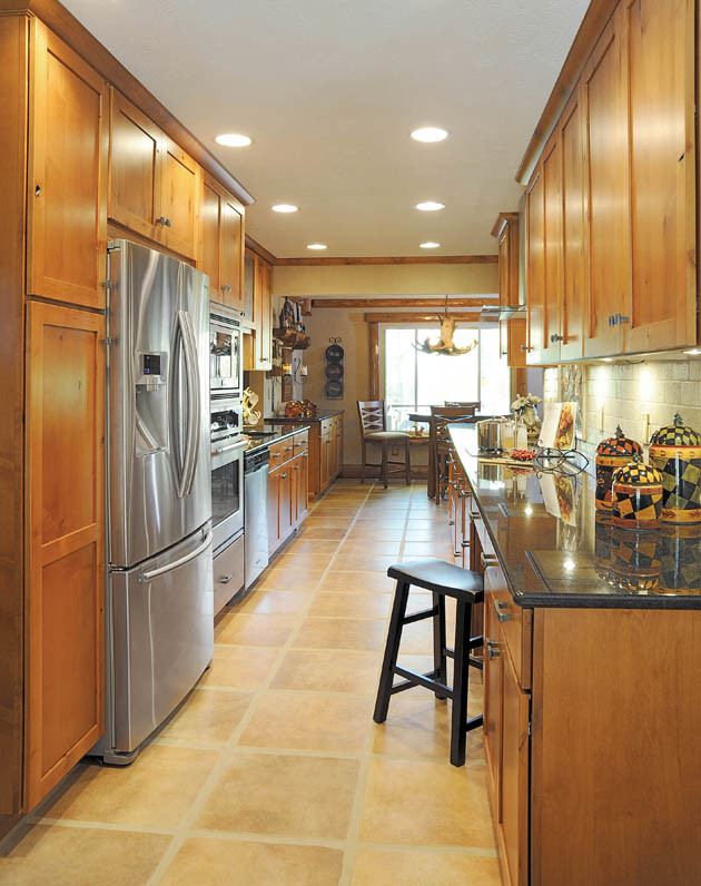 Example of a mountain style galley enclosed kitchen design in Cincinnati with an undermount sink, recessed-panel cabinets, dark wood cabinets, granite countertops, beige backsplash, stone tile backsplash and stainless steel appliances