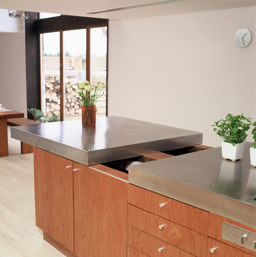 This is an example of a large contemporary kitchen in Hertfordshire with an integrated sink, stainless steel cabinets, stainless steel worktops, stainless steel appliances and an island.