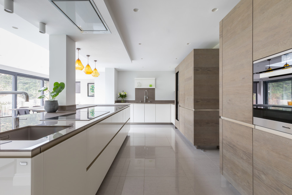 Photo of a large contemporary galley open plan kitchen in Sussex with flat-panel cabinets and an island.