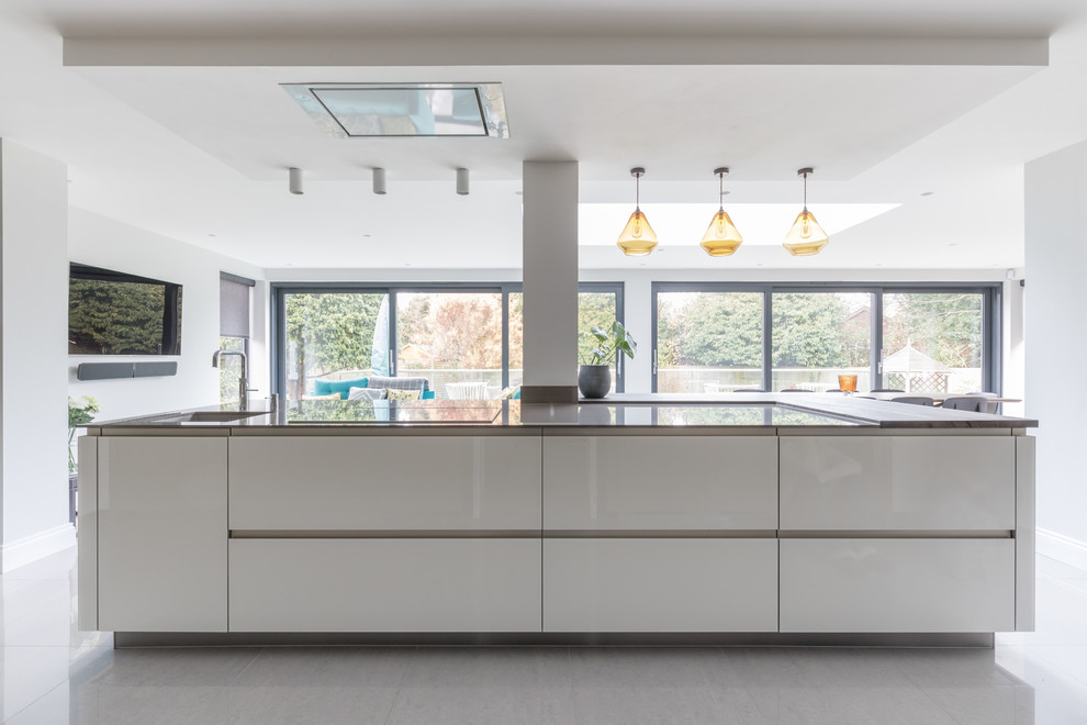 Photo of a large contemporary galley open plan kitchen in Sussex with flat-panel cabinets and an island.