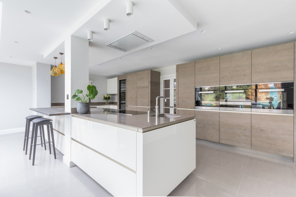 Large contemporary galley open plan kitchen in Sussex with flat-panel cabinets and an island.