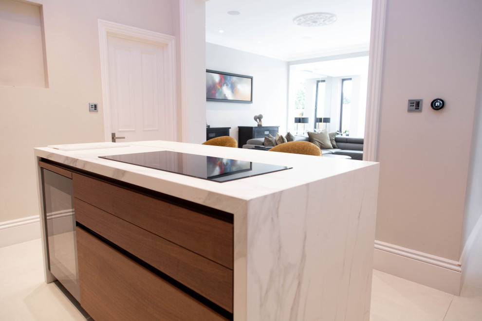 Small contemporary cream and black l-shaped enclosed kitchen in London with a built-in sink, flat-panel cabinets, black cabinets, integrated appliances, ceramic flooring, a breakfast bar, beige floors, white worktops and a coffered ceiling.