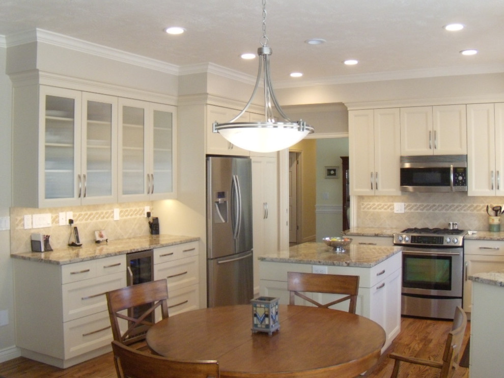 Exempel på ett mellanstort klassiskt beige beige kök, med en dubbel diskho, luckor med infälld panel, vita skåp, granitbänkskiva, beige stänkskydd, stänkskydd i porslinskakel, rostfria vitvaror, mellanmörkt trägolv, en köksö och brunt golv