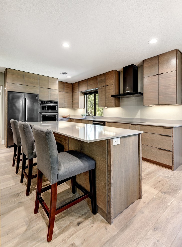 Example of a large minimalist l-shaped light wood floor and beige floor eat-in kitchen design in Austin with an undermount sink, flat-panel cabinets, light wood cabinets, quartz countertops, black appliances, an island, gray backsplash and stone slab backsplash