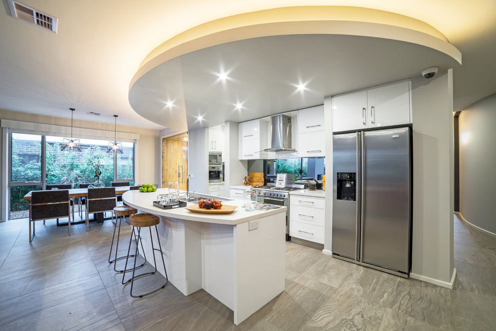 Imagen de cocina comedor contemporánea con armarios con paneles lisos, puertas de armario blancas, electrodomésticos de acero inoxidable y una isla