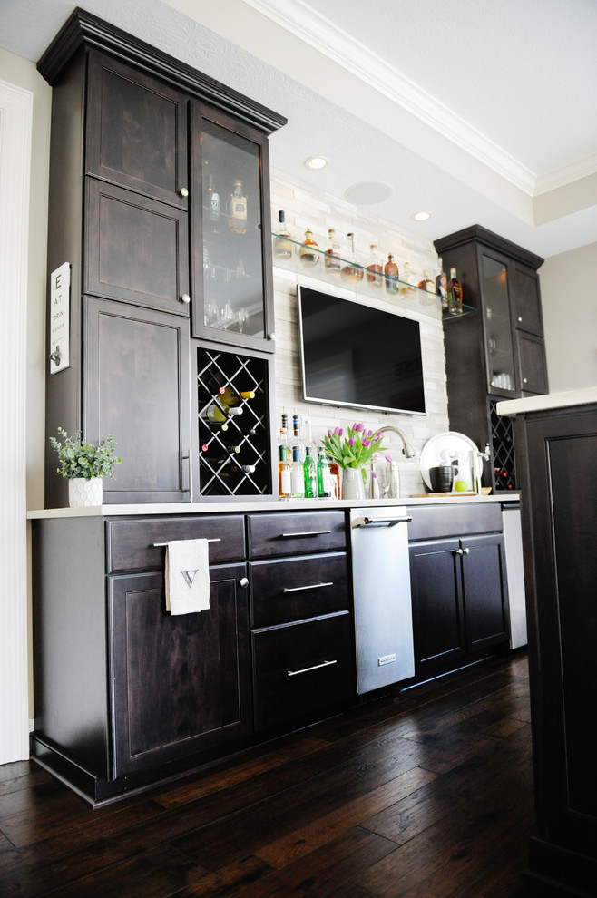 This is an example of a medium sized contemporary single-wall home bar in Columbus with shaker cabinets, black cabinets, engineered stone countertops, grey splashback, cement tile splashback, dark hardwood flooring and brown floors.