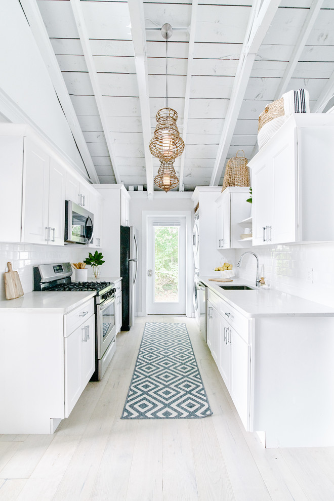 This is an example of a small nautical galley kitchen pantry in Providence with a single-bowl sink, recessed-panel cabinets, white cabinets, granite worktops, white splashback, ceramic splashback, stainless steel appliances, light hardwood flooring, no island, beige floors and white worktops.