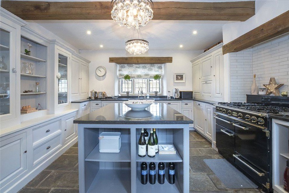 Inspiration for a mid-sized cottage u-shaped gray floor enclosed kitchen remodel in Other with a farmhouse sink, shaker cabinets, gray cabinets, subway tile backsplash, black appliances, an island and black countertops