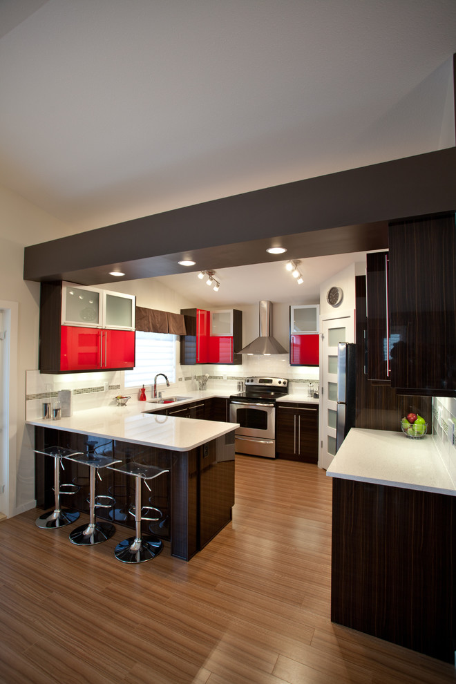Foto de cocinas en U actual con puertas de armario rojas, armarios con paneles lisos, electrodomésticos de acero inoxidable y barras de cocina