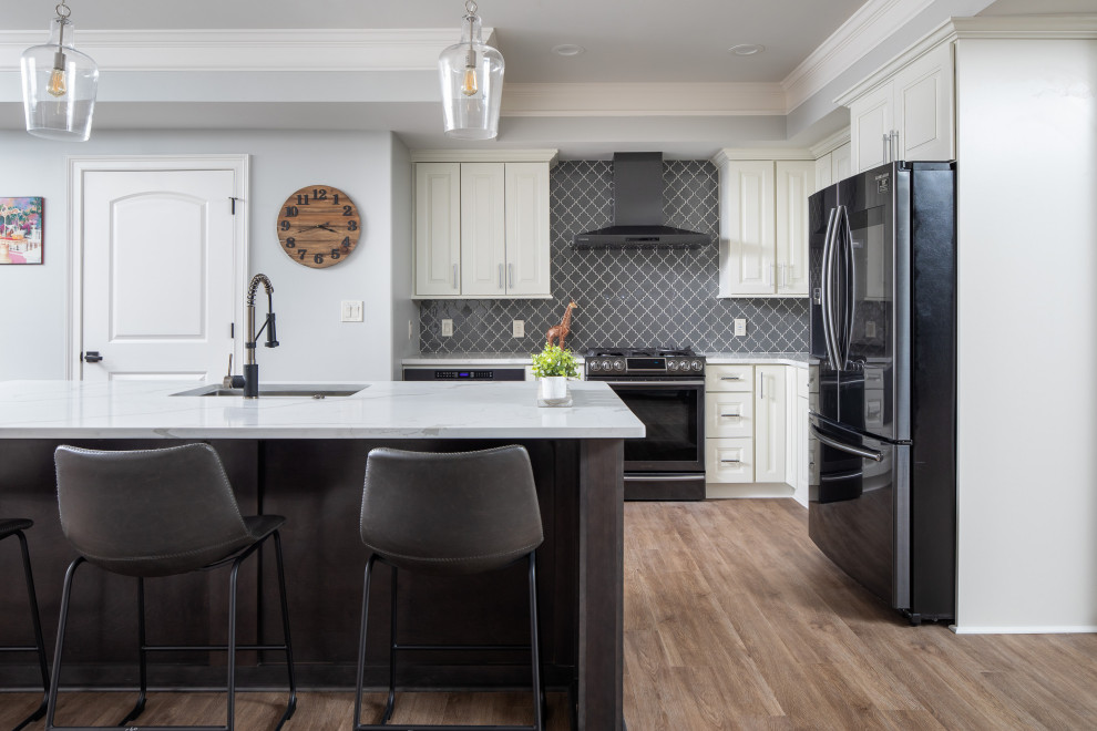 This is an example of a medium sized classic l-shaped kitchen/diner in Atlanta with a submerged sink, raised-panel cabinets, beige cabinets, engineered stone countertops, grey splashback, glass tiled splashback, black appliances, laminate floors, an island, beige floors and white worktops.