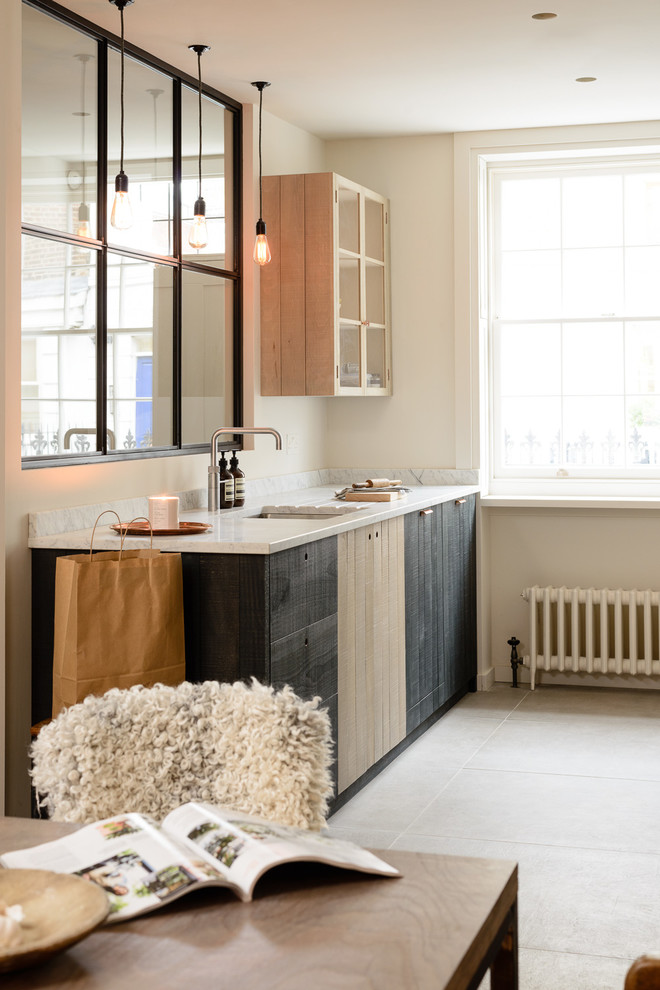 Zweizeilige, Kleine Moderne Wohnküche ohne Insel mit integriertem Waschbecken, flächenbündigen Schrankfronten, Granit-Arbeitsplatte, Elektrogeräten mit Frontblende und hellem Holzboden in London