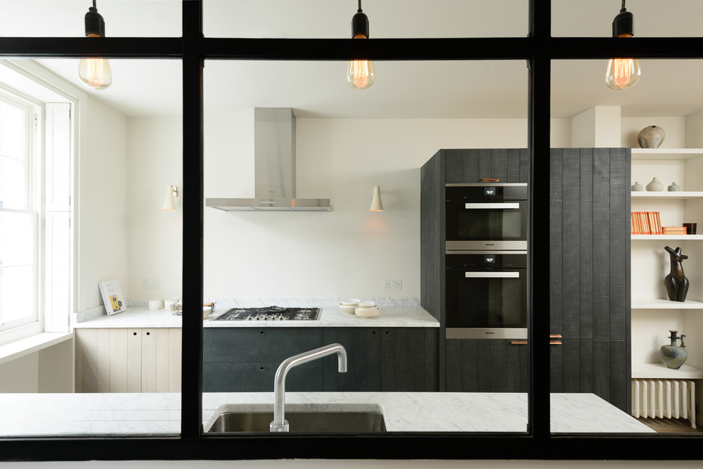 Inspiration for a small contemporary galley kitchen/diner in London with an integrated sink, flat-panel cabinets, granite worktops, integrated appliances, light hardwood flooring and no island.
