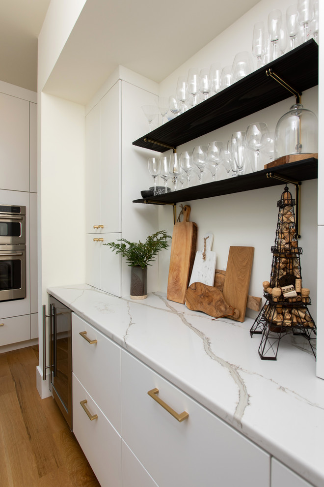 Cette image montre une cuisine rustique avec des portes de placard blanches, un plan de travail en granite et parquet clair.