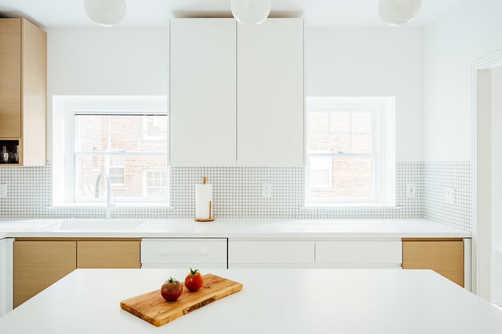 This is an example of a medium sized scandi l-shaped kitchen/diner in Salt Lake City with a submerged sink, flat-panel cabinets, white cabinets, white splashback, white appliances, an island, grey floors and white worktops.