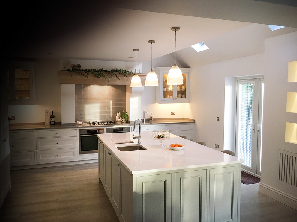 This is an example of a large rural single-wall open plan kitchen in Other with a submerged sink, beaded cabinets, white cabinets, granite worktops, grey splashback, ceramic splashback, black appliances, vinyl flooring and an island.