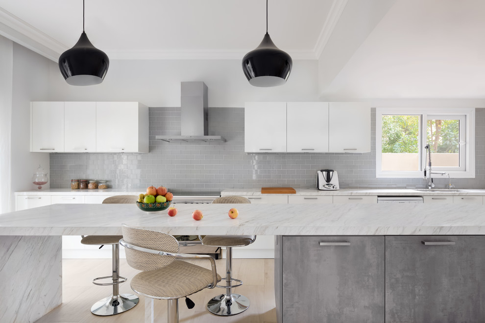 Inspiration for a traditional galley kitchen in Other with a submerged sink, flat-panel cabinets, grey cabinets, marble worktops, grey splashback, metro tiled splashback, stainless steel appliances, light hardwood flooring, an island, beige floors and white worktops.