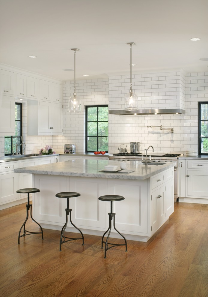 Design ideas for a contemporary kitchen in New York with white cabinets, medium hardwood flooring and an island.