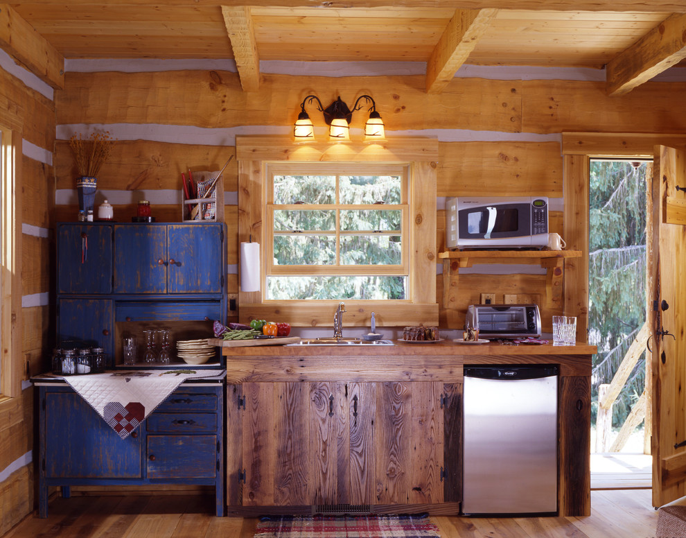 Foto de cocina lineal rural pequeña abierta sin isla con encimera de madera, electrodomésticos de acero inoxidable y suelo de madera clara