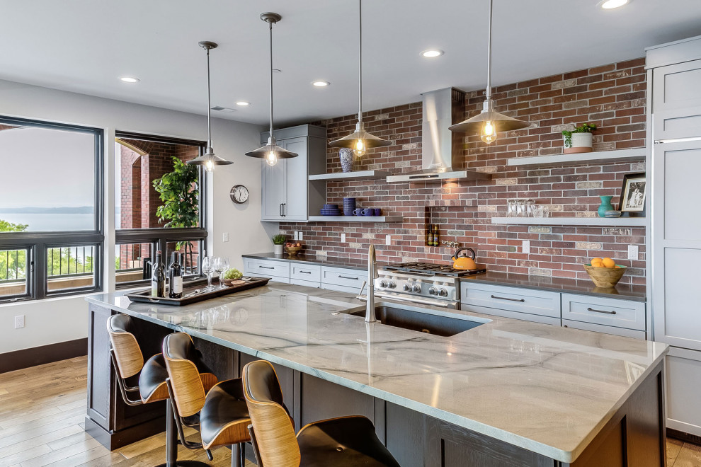 Example of a transitional galley medium tone wood floor and brown floor kitchen design in Other with an undermount sink, shaker cabinets, gray cabinets, multicolored backsplash, brick backsplash, paneled appliances and gray countertops
