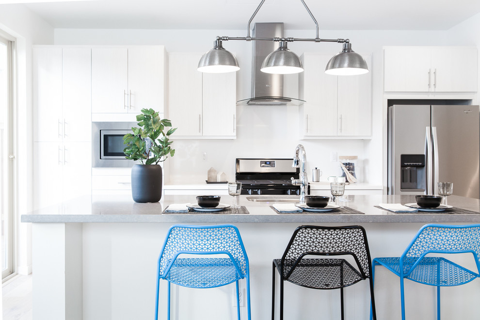 Moderne Küche mit Unterbauwaschbecken, flächenbündigen Schrankfronten, weißen Schränken, Küchenrückwand in Weiß, Küchengeräten aus Edelstahl und Kücheninsel in Sacramento