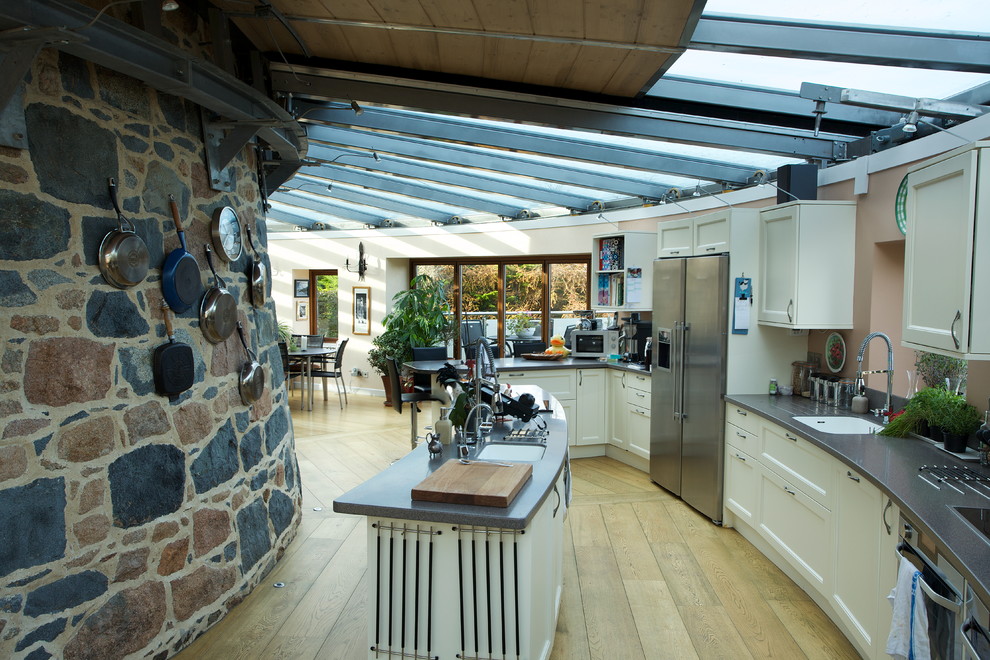 Esempio di una cucina design con ante in stile shaker, ante bianche, elettrodomestici in acciaio inossidabile e pavimento in legno massello medio