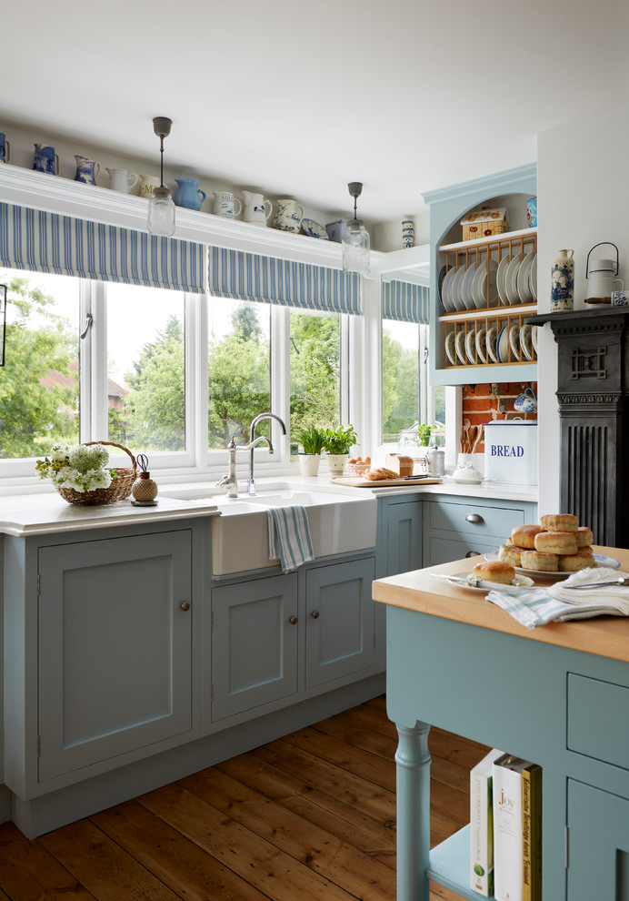 Modelo de cocina clásica grande con armarios estilo shaker, puertas de armario azules, encimera de cuarcita, suelo de madera en tonos medios y una isla