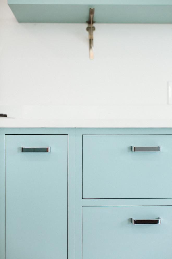 Modern inredning av ett vit linjärt vitt kök och matrum, med en undermonterad diskho, släta luckor, blå skåp, bänkskiva i kvarts, vitt stänkskydd, rostfria vitvaror, terrazzogolv, en köksö och vitt golv
