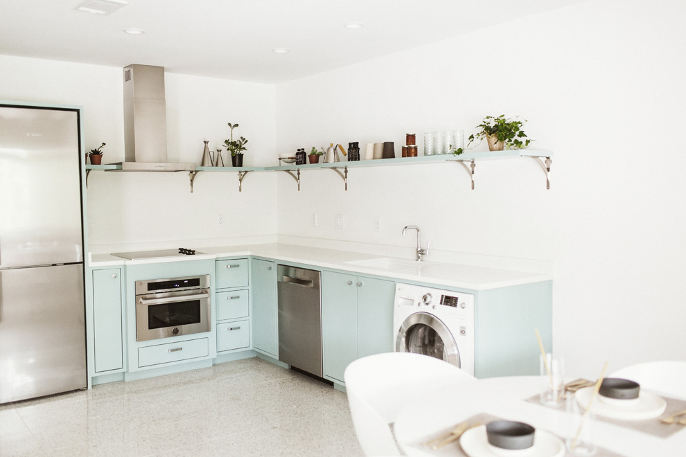 Inredning av ett modernt vit vitt kök, med en undermonterad diskho, släta luckor, blå skåp, bänkskiva i kvarts, vitt stänkskydd, rostfria vitvaror, terrazzogolv och vitt golv