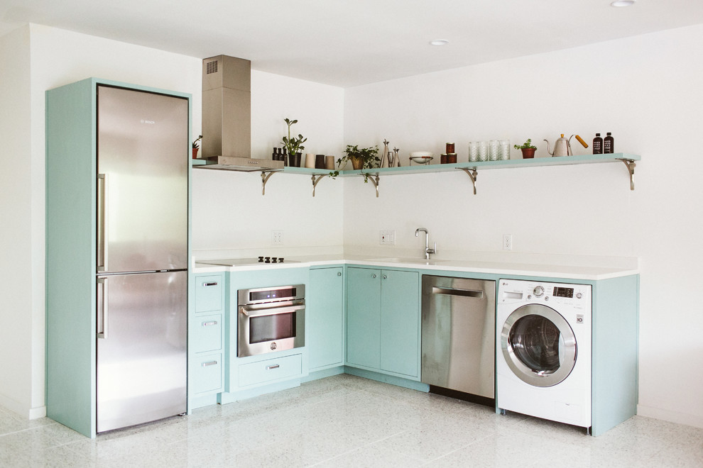 Bild på ett funkis vit linjärt vitt kök och matrum, med en undermonterad diskho, släta luckor, blå skåp, bänkskiva i kvarts, vitt stänkskydd, rostfria vitvaror, terrazzogolv, en köksö och vitt golv