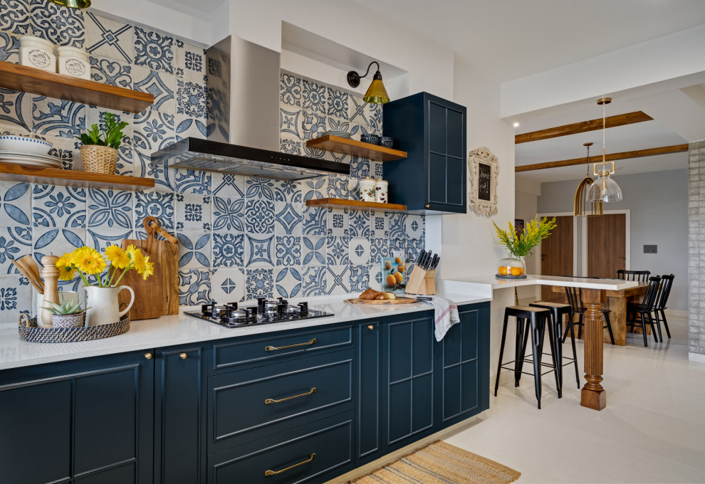 Mediterrane Wohnküche mit Schrankfronten mit vertiefter Füllung, blauen Schränken, Küchenrückwand in Blau, beigem Boden und weißer Arbeitsplatte in Bangalore