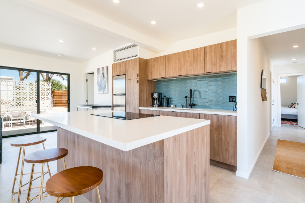 Medium sized contemporary galley open plan kitchen in Other with a submerged sink, flat-panel cabinets, medium wood cabinets, blue splashback, stainless steel appliances, an island, beige floors, white worktops, composite countertops, ceramic splashback and porcelain flooring.