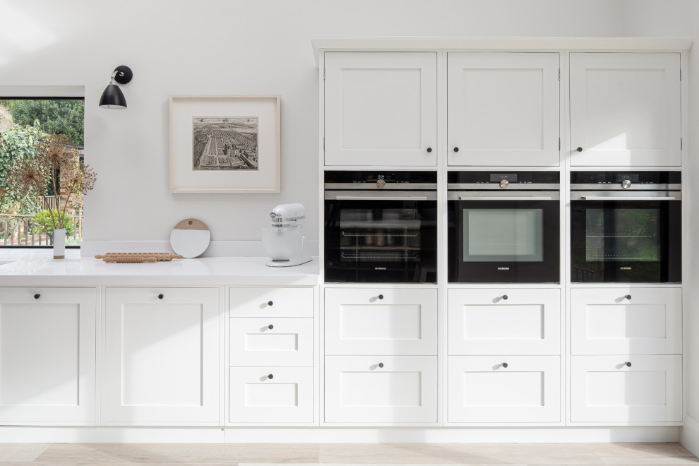 This is an example of a rustic open plan kitchen in Kent with shaker cabinets, white cabinets and an island.