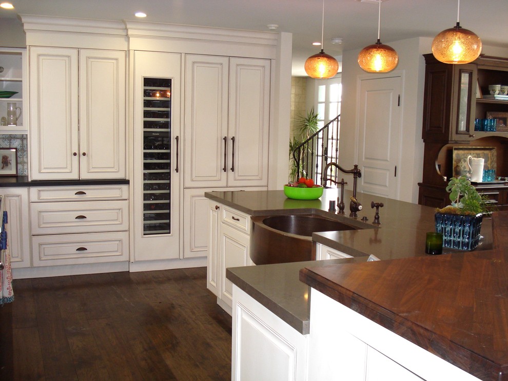 Example of a mid-sized classic l-shaped dark wood floor eat-in kitchen design in Los Angeles with raised-panel cabinets, white cabinets, multicolored backsplash, ceramic backsplash, stainless steel appliances, an island, a farmhouse sink and wood countertops